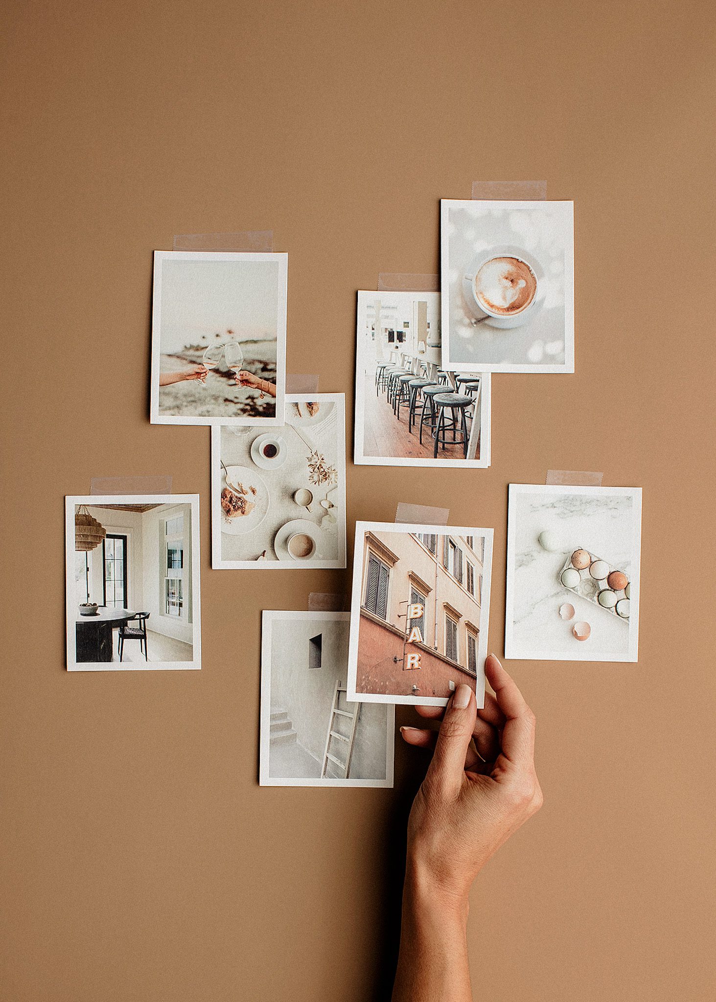 hand sorting through printed photographs on tan surface