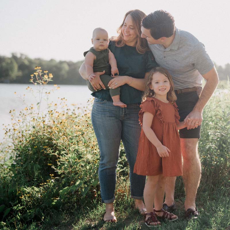 Family of four in front of field and lake